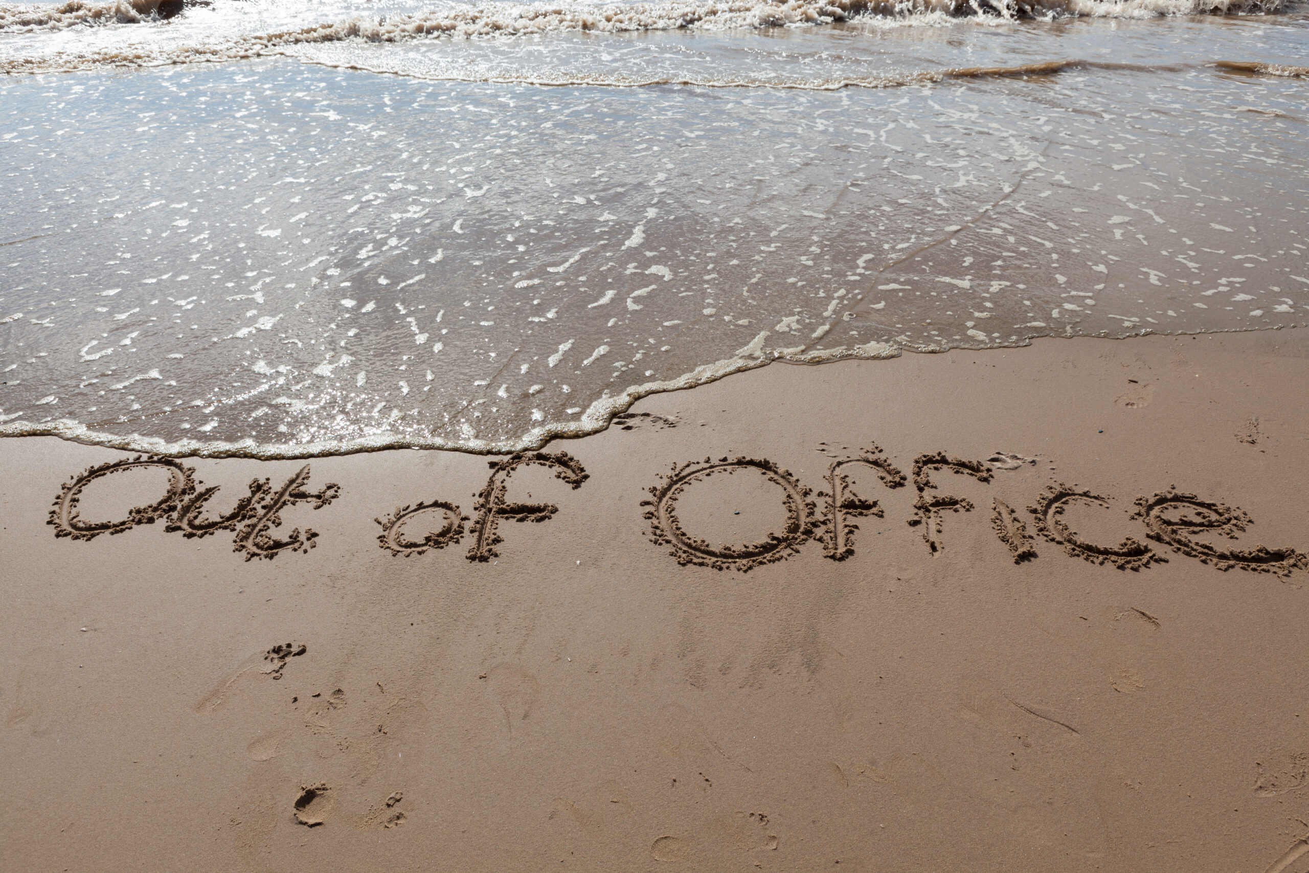Out of Office written in sand.