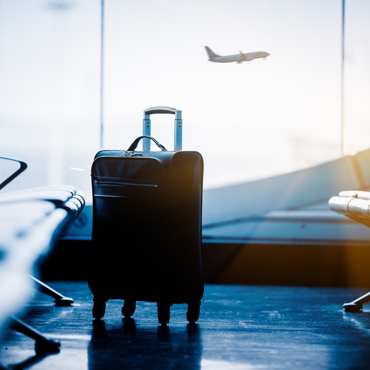 airport waiting area with suitcase and plane in background
