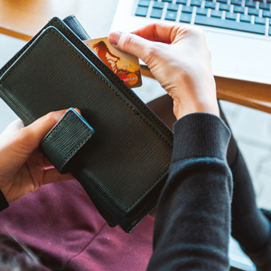 Woman at a laptop computer removing credit card from wallet